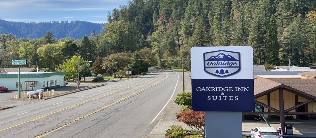 Oakridge Inn and Suites sign with forested hills
